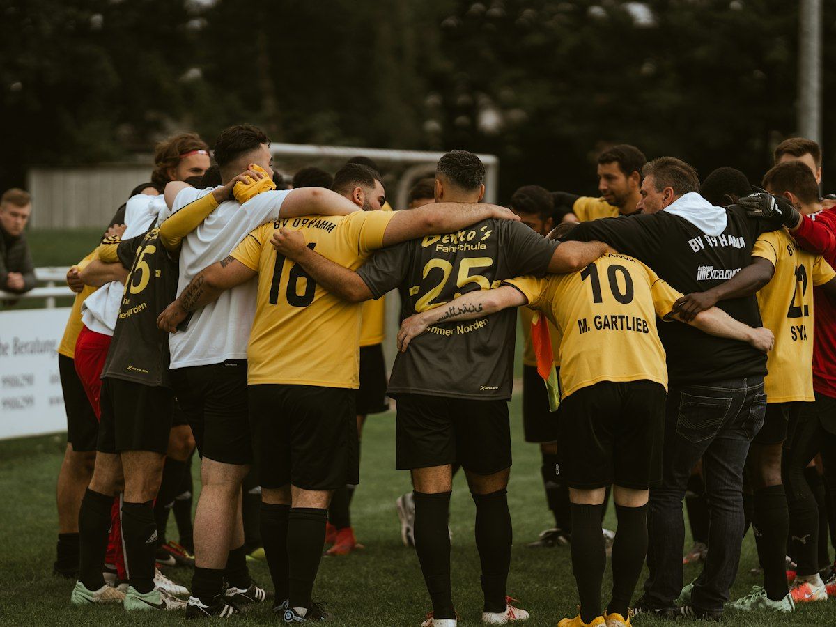 Fußballmannschaft steht im Kreis zusammen